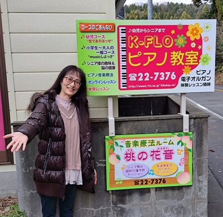 教室の看板の前に立つ菊美先生